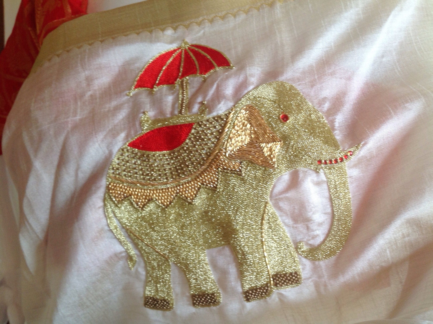 Offwhite semi silk saree with elephant hand embroidery and unstitched red pure silk brocade blouse with elephant weave